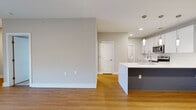 This thoughtfully designed single-floor residence offers a clean, contemporary aesthetic throughout. The open-concept layout seamlessly connects the living area to the kitchen, which serves as a true centerpiece of the home. The kitchen is outfitted with crisp white shaker cabinetry, a striking marble-veined quartz countertop island, a stainless steel undermount sink with a professional-style faucet, and a full suite of stainless steel appliances including a range, over-the-range microwave, and dishwasher. Warm wood-look flooring flows through the main living areas, complemented by neutral warm-gray walls and recessed lighting paired with elegant pendant lights above the island. The bedrooms feature plush carpeting, ceiling fans, and windows with blinds that invite natural light. A generously sized walk-in closet with wire shelving provides excellent storage. The space also includes a dedicated in-unit laundry room with a full-size washer and dryer, adding everyday convenience. A sliding glass door in the living area opens to a private balcony. Throughout, clean white trim, neutral tones, and modern finishes create a bright, cohesive, and move-in-ready environment.