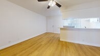 This 450 square foot apartment in Los Angeles offers a thoughtful layout maximizing space efficiency. The single-floor design encompasses one bedroom (140 sq ft), one bathroom, and an open-concept living area. The interior is characterized by bright, white walls and warm wood flooring throughout, creating a cohesive and inviting atmosphere.

The main living space features a ceiling fan for improved air circulation and comfort. Large windows allow natural light to flood the area, enhancing the sense of spaciousness. The kitchen, while compact, is integrated seamlessly into the living area, with a partial wall separation providing definition without compromising the open feel.

The bathroom boasts modern fixtures, including a glass-enclosed shower with a sleek chrome towel bar. Built-in storage solutions are evident in various areas of the apartment, optimizing the use of available space. The bedroom, though modest in size, offers ample room for essential furniture and includes window treatments for privacy.

Overall, this apartment presents a well-designed living solution that balances functionality with style, ideal for those seeking a cozy yet contemporary urban dwelling in Los Angeles.