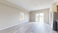 Located at 6916 Fulton St in San Diego's Linda Vista neighborhood, this single-floor unit presents a clean, modern aesthetic throughout. The open living area is finished with light gray wood-look flooring and neutral warm-beige walls, creating a bright and airy atmosphere. A large sliding glass door floods the space with natural light and provides direct access to an outdoor area, while a side window offers additional ventilation and views of the surrounding neighborhood. Recessed ceiling lights complement the natural light throughout.

The kitchen is well-appointed with rich dark-walnut cabinetry, light countertops, and a full suite of stainless steel appliances, including a refrigerator, electric range, over-the-range microwave, and dishwasher. A deep single-basin sink with a brushed nickel faucet anchors the workspace.

The bathroom features wood-look flooring consistent with the rest of the unit, a dark-wood vanity with a white countertop, and accessibility grab bars near the toilet and shower area. A window provides natural light and ventilation.

A dedicated laundry area houses a stacked washer and dryer unit, adding everyday convenience. An electrical panel is also accessible within the unit. The overall design is cohesive and contemporary, making this a functional and well-finished space.
