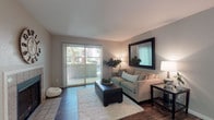 This single-floor residence offers a thoughtfully designed layout with a comfortable blend of style and functionality. The living room serves as the heart of the space, featuring rich hardwood-style flooring, neutral toned walls, and a large sliding glass door fitted with vertical blinds that opens to a private balcony, allowing an abundance of natural light and outdoor views. A bold framed mirror anchors one wall, adding depth to the room.

The kitchen is efficiently arranged with warm wood cabinetry, light countertops, and a full suite of stainless steel appliances, including a range, microwave, refrigerator, and dishwasher, all set atop durable wood-style flooring. Adjacent to the kitchen, the dining area benefits from natural light through a dedicated window and features a ceiling fan overhead, creating a pleasant space for everyday meals.

The bedroom is a tranquil retreat with plush carpeting, soft ambient lighting, and a window that frames greenery from outside. Two bathrooms complete the unit — one featuring a wide vanity with light wood cabinetry and wood-style flooring, and the other offering an extended countertop with ample sink space and a shower. Together, these spaces create a cohesive, move-in ready home with consistent modern finishes throughout.