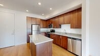 This thoughtfully designed 1-bedroom, 1-bathroom residence offers a comfortable and functional layout across a single floor. The open-concept kitchen and living area serves as the heart of the home, showcasing rich warm-toned cabinetry that extends floor to ceiling, granite countertops, and a full suite of stainless steel appliances including a refrigerator, range, microwave, and dishwasher. A central kitchen island provides additional prep space and casual seating, while light bamboo-style hardwood flooring flows seamlessly throughout the entire unit, adding warmth and continuity.

The spacious bedroom is bathed in natural light from large windows with views of the surrounding neighborhood, and features a ceiling fan for year-round comfort. The closet offers dedicated storage space, keeping the bedroom uncluttered and functional.

The bathroom is clean and modern, featuring a tiled walk-in shower with sliding glass doors, a vanity with warm wood cabinetry, and coordinating hardwood-style flooring that ties the space together. Recessed lighting throughout the unit ensures a bright, welcoming ambiance in every room. Overall, the residence presents a cohesive, contemporary aesthetic with practical finishes suited for comfortable everyday living.