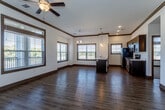 Located at 15201 NW Brink-Myer Rd in Parkville, Missouri, this single-floor unit offers a thoughtfully designed open-concept layout finished with contemporary details throughout. Rich hardwood-style flooring flows through the main living and kitchen areas, complemented by dark wood crown molding and window trim that lend a polished, cohesive aesthetic.

The kitchen is a standout feature, centered around a large island with a white quartz countertop, undermount sink, and pendant lighting above. Dark espresso cabinetry lines the walls alongside a full suite of stainless steel appliances, including a refrigerator, electric range, and over-the-range microwave. The kitchen opens seamlessly into the generous living area, which is bathed in natural light from multiple large windows and finished with a ceiling fan overhead.

The bedrooms offer plush carpet flooring, ceiling fans, and large windows that frame outdoor views. Both full bathrooms feature wood-toned vanities with quartz countertops, tub-shower combinations, and resilient vinyl plank flooring. A dedicated laundry room houses a full-size top-load washer and dryer with overhead shelving for added storage. Stylish two-panel interior doors with modern hardware complete this well-appointed space.