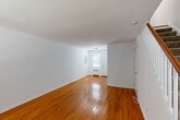 Located at 126 Litton Ave in Groton, CT, this two-story home offers a well-organized layout spread across two floors. The main level features a bright, open living room with gleaming hardwood floors that flow throughout, crisp white walls, and natural light streaming through the front entrance. The living area connects to a dedicated dining space, creating a cohesive and functional layout. The kitchen stands out as a notable highlight, outfitted with rich dark cabinetry, granite countertops, a stone tile backsplash, stainless steel appliances including a range, dishwasher, and refrigerator, and neutral tile flooring. A laundry area and multiple closets add to the practicality of the home. The full bathroom is finished in clean white tile with a tub-shower combination, a vanity with sink, and a window for natural ventilation. The upper floor houses the bedroom, a comfortable and well-lit room with hardwood floors, a radiator for warmth, and windows overlooking the surrounding greenery. Outside, a wooden deck with railing offers views of mature trees and a quiet, tree-lined street, providing a peaceful outdoor retreat. The home also includes a great room and hallway, rounding out a complete and livable floor plan.