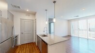 This thoughtfully designed 2-bedroom, 2-bathroom residence in Phoenix, AZ (85085) offers a modern, open-concept layout with clean lines and contemporary finishes throughout. The combined kitchen and living area forms the heart of the home, anchored by a granite-topped kitchen island with a stainless steel undermount sink and stylish pendant lighting overhead. The kitchen is equipped with stainless steel appliances — including a refrigerator, range, and microwave — complemented by two-tone cabinetry and matching granite countertops. Wood-style flooring runs through the main living areas, adding warmth to the bright, white-walled interior. The primary bedroom features plush carpeting and access to a well-appointed en-suite bathroom, which includes a dual-sink vanity with granite counters, grey cabinetry, a walk-in glass-enclosed shower, and wood-style flooring. A spacious walk-in closet with multi-level hanging rods provides ample storage. The second bedroom also features soft carpeting and generous proportions. Both bedrooms are bathed in natural light. A dedicated in-unit laundry room with a washer and dryer adds convenience, while a hallway connects all spaces efficiently. The overall ambiance is clean, modern, and move-in ready.