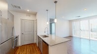 This thoughtfully designed 2-bedroom, 2-bathroom residence in Phoenix, AZ (85085) offers a modern, open-concept layout with clean lines and contemporary finishes throughout. The combined kitchen and living area forms the heart of the home, anchored by a granite-topped kitchen island with a stainless steel undermount sink and stylish pendant lighting overhead. The kitchen is equipped with stainless steel appliances — including a refrigerator, range, and microwave — complemented by two-tone cabinetry and matching granite countertops. Wood-style flooring runs through the main living areas, adding warmth to the bright, white-walled interior. The primary bedroom features plush carpeting and access to a well-appointed en-suite bathroom, which includes a dual-sink vanity with granite counters, grey cabinetry, a walk-in glass-enclosed shower, and wood-style flooring. A spacious walk-in closet with multi-level hanging rods provides ample storage. The second bedroom also features soft carpeting and generous proportions. Both bedrooms are bathed in natural light. A dedicated in-unit laundry room with a washer and dryer adds convenience, while a hallway connects all spaces efficiently. The overall ambiance is clean, modern, and move-in ready.
