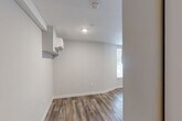 Located at 859 McCallie Ave in Chattanooga, Tennessee, this single-level studio offers a thoughtfully designed layout that maximizes every square foot of its compact footprint. The main living area features rich, wood-grain luxury vinyl plank flooring that runs throughout, complemented by crisp white walls and recessed lighting that keep the space feeling bright and open. A window allows natural light to filter in, adding warmth to the room's clean, neutral palette. A wall-mounted mini-split heating and cooling unit provides efficient, year-round climate control.

The kitchen is well-appointed with white shaker-style cabinetry extending to the upper walls, offering generous storage. Stainless steel appliances — including a gas range and over-the-range microwave — pair with light-toned countertops and a stainless sink to create a functional and attractive cooking space. The layout makes efficient use of an L-shaped counter configuration.

A dedicated open closet area with a hanging rod provides convenient clothing storage within the main living space. The full bathroom is finished in a clean, contemporary style, featuring large-format tile flooring, a walk-in shower/tub combination, a dark wood vanity with a white sink, and bright overhead lighting. The overall design of this space is modern, functional, and move-in ready.