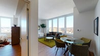 Located at 45 Main St in Yonkers, NY, this contemporary high-rise unit offers a thoughtfully designed open-concept layout filled with abundant natural light. The living and dining area is a standout, anchored by a wall of large floor-to-ceiling windows that frame sweeping panoramic views of the Yonkers skyline. Light hardwood flooring runs throughout, complementing the clean, modern aesthetic of the white walls and smooth ceilings.

The kitchen is sleek and functional, featuring dark cabinetry, ample counter space, stainless steel appliances, and a tall window that captures stunning elevated city views — a rare and striking detail.

The primary bedroom is a serene retreat, highlighted by large windows overlooking the Hudson River and surrounding landscape, providing a tranquil backdrop. The primary bathroom is elegantly appointed with a glass-enclosed walk-in shower, large-format tile, a dual-sink vanity with warm wood cabinetry, and contemporary chrome fixtures.

The second bedroom is bright and comfortable, with its own generous window offering expansive city views. A second full bathroom serves this room, featuring neutral tile flooring, a wood-toned vanity, and a shower-tub combination.

Overall, this high-rise unit combines modern finishes, an efficient layout, and remarkable elevated views to create a refined and comfortable urban living space.
