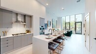 Located at 3030 Potomac Ave in Arlington, VA, this contemporary two-story residence offers 2 bedrooms and 3 bathrooms across two well-proportioned floors. The main level centers on a seamlessly integrated living, dining, and kitchen area bathed in natural light from dramatic floor-to-ceiling windows that frame outdoor views. The chef's kitchen is outfitted with sleek gray cabinetry, stainless steel appliances including a gas cooktop and double wall ovens, a stainless steel range hood, and a large white waterfall island with bar seating—ideal for both cooking and casual dining. The living area is bright and airy, with soaring ceilings and light wood flooring that flows throughout. The upper floor houses both bedrooms, each featuring generous windows with outdoor views, ample closet space, and access to well-appointed bathrooms. The primary bedroom offers a private, serene retreat with abundant natural light. A dedicated laundry area with stacked washer and dryer adds everyday convenience. With six closets distributed across both levels, storage is plentiful. The clean, neutral palette, modern fixtures, and open layout create a polished and functional living environment throughout this thoughtfully designed Arlington residence.