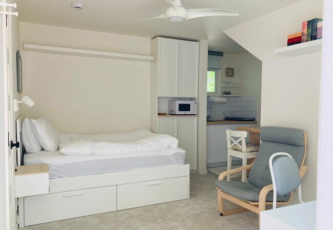 view showing bed, armchair, bookcase, microwave, opening to kitchenette - 626 Bonair Way