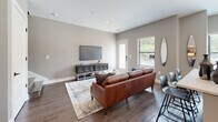 This two-story residence in Roswell, GA offers a well-designed layout across two floors, combining modern finishes with functional living spaces. The main floor features an open-concept kitchen and living area with rich hardwood-style flooring throughout. The kitchen is appointed with white shaker cabinetry, quartz countertops, a subway tile backsplash, stainless steel appliances, a center island, and pendant lighting. A bright dining nook with large windows overlooks the outdoors, while the adjacent living room provides a welcoming gathering space with access to a private exterior door and natural light from multiple windows. Upstairs, the primary bedroom offers plush carpeting, dual windows, a ceiling fan, and a spacious walk-in closet with built-in shelving. Its en-suite bathroom is a standout feature, showcasing dark hardwood-style floors, a dual-sink vanity with white cabinetry and quartz counters, and a glass-enclosed walk-in shower clad in large-format marble-look tile with matte black fixtures. The second bedroom is equally inviting, with soft carpet, dual windows, and a ceiling fan. Four full bathrooms and two closets ensure ample storage and convenience throughout this thoughtfully appointed Roswell home.