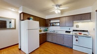 Located at 1600 W Bradley Ave in Champaign, IL, this efficiently designed one-bedroom, one-bathroom unit offers a practical and comfortable single-floor layout. The combined kitchen and living area forms the heart of the home, with the kitchen featuring warm wood-toned cabinetry, white appliances including a refrigerator and electric range, a double-basin sink, and a ceiling fan overhead. A sliding-door closet near the kitchen entry provides convenient pantry storage, and hardwood-style flooring ties the space together seamlessly. The living room flows naturally from the kitchen, offering carpeted flooring, a wall-mounted air conditioning unit, and a window that brings in natural light. A defined dining area provides space for a small table and chairs. The bedroom is a comfortable, well-proportioned retreat with plush carpet, a window with blinds, a wall-mounted air conditioning unit, and a closet accessed via a wood-panel door. The full bathroom features a tiled tub-shower combination with white tile surround and standard fixtures. Throughout the unit, neutral wall tones and warm wood accents create a welcoming and functional living environment suited for everyday comfort.