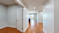 This well-appointed 2-bedroom, 1-bathroom residence in Austin, TX offers a thoughtfully designed single-floor layout with a clean, modern aesthetic throughout. The entryway opens into a bright hallway with warm wood-style flooring and recessed lighting, leading to an open living area bathed in natural light from large sliding glass doors that frame sweeping views of the Austin skyline and lush treetops beyond.

The kitchen is a standout feature, showcasing rich dark cabinetry, granite countertops, a subway tile backsplash, and a full suite of stainless steel appliances, including a French door refrigerator, electric range, built-in microwave, and dishwasher. Pendant lighting adds a refined finishing touch.

The spacious primary bedroom features plush carpeting, a ceiling fan, and a large picture window offering serene treetop views. The second bedroom is finished with the same wood-style flooring found throughout the common areas, providing flexibility as a guest room or home office.

The bathroom is elegantly appointed with dark wood cabinetry, a wide vanity with an undermount sink, and tile flooring. A dedicated closet with built-in shelving provides ample storage. The unit also includes an in-unit laundry area, completing this comfortable and functional Austin residence.