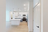 Located at 6735 Standifer Gap Rd in Chattanooga, TN, this well-appointed single-story home offers three bedrooms, two bathrooms, and a thoughtfully designed open-concept layout. The kitchen and living area form the heart of the home, showcasing a central island with a crisp white countertop, two-tone cabinetry featuring white upper cabinets and gray lower cabinets, a white subway tile backsplash, and a full suite of stainless steel appliances including a refrigerator with ice maker, range, microwave, and dishwasher. Recessed lighting and brushed nickel pendant lights illuminate the space, while light hardwood-style flooring adds warmth throughout the main living areas. The bathrooms continue the home's modern aesthetic with gray vanity cabinetry, white countertops, large mirrors, and hardwood-style flooring. The bedrooms feature plush carpeting and ceiling fans, and select rooms offer windows with outdoor views of the surrounding greenery, allowing natural light to fill the space. One room includes a glass-paned door opening to an outdoor area with scenic views. The layout is efficient yet comfortable, providing well-defined living spaces within a cohesive, contemporary design palette.