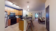 This well-appointed 2-bedroom, 2-bathroom single-floor residence offers a thoughtfully designed open-concept layout that seamlessly connects the kitchen, dining, and living areas. The kitchen is a standout feature, showcasing warm honey-toned cabinetry, dark countertops, a navy tile backsplash, and stainless steel appliances including a refrigerator and over-the-range microwave. A peninsula with seating for three provides a convenient breakfast bar and serves as a natural divider between the kitchen and the carpeted living space. The living room is bright and welcoming, with crown molding, a ceiling fan, large windows that invite natural light, and a private exterior door. Both bedrooms are generously sized, each featuring plush carpet, ceiling fans, and windows with ample natural light. The primary bedroom is particularly spacious, accommodating a king-sized bed with room to spare. Each of the two full bathrooms is finished with warm wood vanities, stone-toned countertops, tub-shower combinations, and tile flooring, offering a clean and functional design. Throughout the residence, a neutral color palette and consistent finishes create a cohesive and inviting atmosphere.