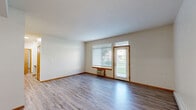 Located at 5420 W Barnes Rd in Spokane, WA, this well-appointed 2-bedroom, 2-bathroom single-floor unit offers a comfortable and functional layout. The living room is bright and spacious, featuring durable wood-style flooring, neutral walls, a textured ceiling, and a wall-mounted HVAC unit. A large window and a private exterior door flood the space with natural light and provide direct access to the beautifully landscaped community grounds, complete with manicured lawns and mature trees. The galley-style kitchen is efficiently designed with warm wood cabinetry, light countertops, a double sink, and white appliances including a refrigerator and range. Both bedrooms are generously sized, with the primary bedroom offering notable square footage, carpet flooring, and a large sliding-door closet. Each bathroom is equipped with wood-tone vanity cabinetry, a tub-shower combination, and wood-style tile flooring. A dedicated laundry area with in-unit washer and dryer adds everyday convenience. Baseboard heating is present throughout, and recessed lighting accents the entryway. The private patio entrance opens to well-kept community green space, enhancing the overall sense of comfort and livability.