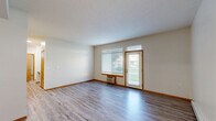 Located at 5420 W Barnes Rd in Spokane, WA, this well-appointed 2-bedroom, 2-bathroom single-floor unit offers a comfortable and functional layout. The living room is bright and spacious, featuring durable wood-style flooring, neutral walls, a textured ceiling, and a wall-mounted HVAC unit. A large window and a private exterior door flood the space with natural light and provide direct access to the beautifully landscaped community grounds, complete with manicured lawns and mature trees. The galley-style kitchen is efficiently designed with warm wood cabinetry, light countertops, a double sink, and white appliances including a refrigerator and range. Both bedrooms are generously sized, with the primary bedroom offering notable square footage, carpet flooring, and a large sliding-door closet. Each bathroom is equipped with wood-tone vanity cabinetry, a tub-shower combination, and wood-style tile flooring. A dedicated laundry area with in-unit washer and dryer adds everyday convenience. Baseboard heating is present throughout, and recessed lighting accents the entryway. The private patio entrance opens to well-kept community green space, enhancing the overall sense of comfort and livability.