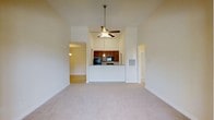 Located at 485 Traebert Cir in Raleigh, NC, this single-floor residence offers an inviting open-concept layout designed for comfortable everyday living. The main living area immediately impresses with soaring vaulted ceilings that amplify the sense of space, complemented by a ceiling fan with integrated lighting that keeps the area well-ventilated and bright. Soft, neutral-toned carpeting extends throughout, adding warmth underfoot and tying the living spaces together cohesively.

At the heart of the home sits a peninsula-style kitchen featuring rich, dark wood cabinetry that provides generous storage. The raised breakfast bar creates a natural divide between the kitchen and living area while offering casual seating. Black appliances, including a refrigerator and microwave, are seamlessly integrated into the cabinetry for a streamlined look.

Arched doorways lead to additional rooms, adding an elegant architectural touch that softens transitions throughout the home. The layout flows naturally between spaces, with hallways connecting to what appear to be private rooms beyond. Neutral wall tones throughout create a clean, versatile backdrop ready for personalization. Overall, this single-story home balances functional design with notable architectural details, making it a welcoming and practical living environment in Raleigh.