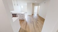Located on the 9th floor at 830 9 Ave SW in the heart of downtown Calgary, this one-bedroom, one-bathroom unit offers a well-designed open-concept layout with a clean, contemporary aesthetic throughout. Light-toned laminate flooring flows seamlessly across the entire space, complementing the crisp white walls and creating a bright, cohesive feel.

The kitchen is a standout feature, designed in a galley style with white cabinetry accented by black hardware, light quartz countertops, and a full suite of stainless steel appliances including a range, microwave, and refrigerator. Pendant lighting above the kitchen island and track lighting overhead add both function and style, while the open pass-through connects effortlessly to the living area.

The living room is an open, versatile space bathed in natural light from the windows, offering a comfortable and adaptable area for everyday living.

The bedroom features two windows with vertical blinds that frame views of the Calgary skyline, filling the room with natural light. The bathroom is finished in neutral tones with tile flooring, a full soaker tub and shower combination, and white vanity cabinetry. A hallway provides practical connectivity between all rooms, completing this efficiently designed urban residence.