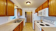 Located at 642 Highpointe Dr in Allegan, Michigan, this two-story, two-bedroom, two-bathroom home offers a well-organized layout across two floors. The main level, which comprises the majority of the living space, features a galley-style kitchen outfitted with warm oak cabinetry, a double-basin sink, coil-burner range, refrigerator, built-in microwave, and tile flooring. In-unit laundry is conveniently accessible directly from the kitchen. The main living area is highlighted by soaring vaulted ceilings, soft neutral carpet, and a sliding glass door fitted with vertical blinds that allows natural light to flood the space. A carpeted staircase with a polished wood handrail connects the two floors. Both bedrooms are carpeted and feature neutral walls, baseboard heating, and windows that invite natural light. The primary bedroom offers a generous footprint, while the second bedroom provides a comfortable, functional space. The two bathrooms are finished with tile flooring and oak vanities; one features a full soaking tub and shower combination. Throughout the home, a clean, neutral palette and practical finishes create a move-in ready environment suited for a variety of living arrangements.