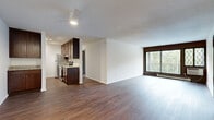 This 2-bedroom, 1-bathroom single-floor residence offers a practical and cohesive layout designed for comfortable living. The open-concept kitchen and living area serves as the heart of the home, where rich dark hardwood-style flooring flows continuously throughout. The kitchen is well-equipped with dark espresso cabinetry, granite-style countertops, stainless steel appliances including a refrigerator, dishwasher, and built-in microwave, and a peninsula that provides additional counter space and separation from the living area. A ceiling fan overhead adds comfort to the living space, which also benefits from a wall-mounted air conditioning unit and access to a balcony with outdoor views.

The two bedrooms are carpeted for warmth and comfort, each featuring closets with bifold doors. The primary bedroom offers a generous footprint, while the second bedroom includes a charming lattice-style window that brings in natural light. Both rooms are finished with clean white walls and neutral tones. The full bathroom includes a tub-shower combination, a wood-framed vanity with granite-style countertop, mosaic tile flooring, and crisp white walls. The overall design is clean, functional, and move-in ready.