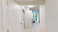 Located at 1698 University Ave in Berkeley, CA, this 2-bedroom, 1-bathroom unit offers a thoughtfully designed single-floor layout with a clean, modern aesthetic throughout. Light wood-tone flooring runs continuously across all rooms, complementing the crisp white walls and creating a bright, cohesive atmosphere.

The hallway serves as the central spine of the unit, connecting all rooms with efficient flow. The spacious primary bedroom is the standout space, offering generous room for a bed, dedicated workspace, and storage, with a large window framing greenery outside and admitting ample natural light. A full-height wardrobe provides substantial built-in storage. The second bedroom is equally well-appointed, featuring floor-to-ceiling black-framed windows that invite in natural light and tree views, paired with a built-in desk area and a mirrored wardrobe.

The kitchen is outfitted with white cabinetry, white appliances including a refrigerator, range, and microwave, and a practical U-shaped layout. A compact dining area sits adjacent, ideal for casual meals. The bathroom features light wood-look flooring, a shower-tub combo with a curtain, a wall-mounted vanity, and a small window for ventilation. The overall design is clean and contemporary, making efficient and comfortable use of the available space.