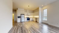 Located at 8015 Boul du St-Laurent in Brossard, QC, this modern 2-bedroom, 1-bathroom unit offers a well-designed open-concept layout with contemporary finishes throughout. Light-toned laminate flooring flows seamlessly across the main living areas, complementing the bright, neutral color palette.

The kitchen is a standout feature, showcasing sleek white cabinetry extending to the ceiling, ample counter space, under-cabinet lighting, and a full suite of stainless steel appliances including a refrigerator, electric range, dishwasher, and built-in microwave. A bold circular pendant light adds a modern focal point.

The living room is bathed in natural light through large floor-to-ceiling windows and sliding glass doors, offering open views of the surrounding neighborhood. The bright, airy atmosphere is further enhanced by recessed lighting.

Both bedrooms are well-proportioned, featuring laminate flooring, generous closet space, and large windows that invite natural light. A wall-mounted mini-split system provides efficient climate control throughout the unit.

The bathroom is finished with large-format tiles, a soaker tub, a separate glass-enclosed shower, a wood-toned vanity, and a mirrored medicine cabinet. A dedicated laundry room houses a full-size Whirlpool front-load washer and dryer with overhead wire shelving for additional storage.