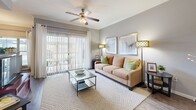 Located in Cypress, TX, this well-appointed single-story unit offers 1 bedroom, 2 bathrooms, and a versatile office space across a comfortable, efficiently organized floor plan. The living room features wood-look flooring, crown molding, and a ceiling fan, creating a warm and inviting atmosphere with ample room for seating and entertaining. Adjacent to the living area, the dining space is highlighted by a corner window arrangement that fills the room with natural light, complemented by a pendant light fixture overhead. The galley-style kitchen is outfitted with dark cabinetry, granite-style countertops, and black appliances including a range, microwave, and refrigerator. The spacious primary bedroom is carpeted for comfort, features a ceiling fan, and receives generous natural light through large windows with blinds. Both bathrooms are finished with dark wood cabinetry, granite-style countertops, and wood-look flooring; one includes a full tub-shower combination. The unit also includes a dedicated office space, a closet for storage, and two hallways that connect the rooms efficiently. Neutral gray walls throughout lend a cohesive, modern aesthetic to the entire space.