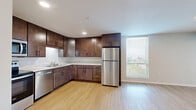 Located at 505 Malcolm Ave SE in Minneapolis, MN, this 1-bedroom, 1-bathroom unit offers a thoughtfully designed floor plan that maximizes every square foot. Light wood-tone flooring runs throughout, creating a warm and cohesive aesthetic across all rooms.

The kitchen is a standout feature, equipped with rich dark wood cabinetry, ample counter space, and a full suite of stainless steel appliances including a refrigerator, range with microwave hood, and dishwasher. Natural light pours in through a large window adjacent to the kitchen, brightening the open dining and living area. Exposed ductwork adds an industrial touch to the living space, which also benefits from multiple windows framing views of the surrounding Minneapolis cityscape.

The bedroom is a comfortable, well-lit retreat with large windows that invite natural light and offer outdoor views. A wide sliding-door closet provides generous storage, complemented by an additional closet nearby. The bathroom features a clean, white soaking tub and shower combination with chrome fixtures. A utility room and additional storage closet round out the practical amenities of this unit, making it both functional and comfortable for everyday living.