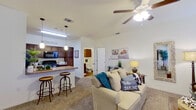 This single-story unit offers a thoughtfully arranged floor plan that maximizes functionality within a compact footprint. The open-concept living and dining area features plush carpeting, a ceiling fan with integrated lighting, and windows that admit natural light, creating a bright and welcoming atmosphere. A dedicated dining space near the entry provides room for a small table and chairs.

The kitchen is equipped with rich dark wood cabinetry, granite-style countertops, and black appliances including a refrigerator, electric range, and built-in microwave. A peninsula with bar seating connects the kitchen to the living area, offering additional counter space and a casual dining option. Pendant lighting and a skylight overhead enhance visibility throughout the kitchen. An in-unit laundry area is conveniently accessible from the kitchen corridor.

The primary bedroom accommodates a full-sized bed comfortably and includes a ceiling fan, a window with natural light, and access to a walk-in closet. The bathroom features wood-look flooring, a dark wood vanity with a granite-style countertop, a large mirror, overhead cabinetry, and a shower-tub combination.