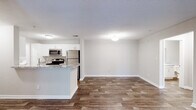 This single-floor residence at 1400 Boxwood Blvd in Columbus, Georgia offers a well-designed layout with a seamless blend of functional and comfortable living spaces. The open-concept living and dining area is anchored by rich, dark wood-look flooring that extends throughout the main living spaces, creating a cohesive and inviting atmosphere. A ceiling fan with a decorative light fixture and a glass door leading to the outdoors fill the living area with natural light and provide convenient outdoor access.

The galley-style kitchen is a standout feature, equipped with stainless steel appliances including a refrigerator, range, microwave, and dishwasher. White cabinetry pairs cleanly with granite-style countertops, and a peninsula with bar seating connects the kitchen to the main living area, ideal for casual dining or entertaining.

The bedrooms offer a quieter retreat, each finished with plush carpeting and windows that invite natural light. The bathrooms are appointed with granite-topped white vanities and the same wood-look flooring found throughout the rest of the home. One bathroom includes a tiled shower-tub combination, while another features a spacious vanity with ample storage. Textured ceilings and neutral wall tones throughout lend a clean, move-in-ready feel to the entire space.