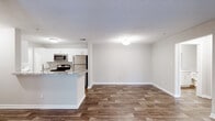 This single-floor residence at 1400 Boxwood Blvd in Columbus, Georgia offers a well-designed layout with a seamless blend of functional and comfortable living spaces. The open-concept living and dining area is anchored by rich, dark wood-look flooring that extends throughout the main living spaces, creating a cohesive and inviting atmosphere. A ceiling fan with a decorative light fixture and a glass door leading to the outdoors fill the living area with natural light and provide convenient outdoor access.

The galley-style kitchen is a standout feature, equipped with stainless steel appliances including a refrigerator, range, microwave, and dishwasher. White cabinetry pairs cleanly with granite-style countertops, and a peninsula with bar seating connects the kitchen to the main living area, ideal for casual dining or entertaining.

The bedrooms offer a quieter retreat, each finished with plush carpeting and windows that invite natural light. The bathrooms are appointed with granite-topped white vanities and the same wood-look flooring found throughout the rest of the home. One bathroom includes a tiled shower-tub combination, while another features a spacious vanity with ample storage. Textured ceilings and neutral wall tones throughout lend a clean, move-in-ready feel to the entire space.