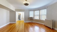 Located in Denver's Capitol Hill neighborhood, this 1-bedroom, 1-bathroom residence showcases a blend of classic architectural character and functional design. The standout feature is the living room's dramatic curved bay window wall, wrapped in elegant crown molding and bathed in natural light. Warm hardwood floors flow throughout the entire space, complemented by neutral tones that create a cohesive, inviting atmosphere. A cast-iron radiator adds a charming period detail to the living area.

The hallways connect each room efficiently, lending the layout a logical, organized flow. The bedroom offers a comfortable, well-proportioned space with a ceiling fan, a natural light window, a radiator, and a dedicated closet accessed through a rich, dark-stained wood door. The kitchen features dark granite countertops, light maple cabinetry, a stainless steel sink, and a classic black-and-white checkered tile floor, providing both style and practicality. A window above the sink brings in natural light.

The bathroom continues the vintage aesthetic with classic white penny tile flooring, subway tile wainscoting, and a decorative radiator cover, accessed through a substantial dark wood door with brass hardware. This residence offers a thoughtfully preserved character throughout.