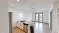 This 560 square foot apartment offers a thoughtful blend of comfort and efficiency in a single-floor layout. The heart of the home is a 170 square foot primary bedroom, providing ample space for relaxation and storage. The room features plush carpeting, a ceiling fan for air circulation, and large windows that flood the space with natural light, creating an open and airy ambiance.

The kitchen is a testament to modern design, boasting sleek white cabinetry, stainless steel appliances, and a functional layout. It includes a refrigerator, built-in microwave, and oven, all arranged for maximum efficiency. The light wood-look flooring in the kitchen adds warmth to the space, while pendant lighting over the kitchen island provides both task lighting and a touch of style.

The living area, while compact, is well-designed with the same attention to detail. It features the same carpeting as the bedroom, ensuring a cohesive look throughout the apartment. The space is versatile, allowing for various furniture arrangements to suit individual needs.

Throughout the apartment, recessed lighting and a neutral color palette create a bright, contemporary atmosphere. The inclusion of a closet ensures adequate storage space, a crucial feature in a compact living environment. This apartment is an excellent example of how thoughtful design can maximize the functionality and comfort of a smaller living space.
