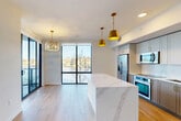 Located at 1532 S Federal Hwy in Boynton Beach, FL, this thoughtfully designed 2-bedroom, 3-bathroom residence offers a seamless blend of modern aesthetics and functional living. The open-concept main living area features light wood-look tile flooring, floor-to-ceiling black-framed sliding glass doors, and expansive windows that flood the space with natural light while framing stunning views of both a resort-style pool and the waterfront beyond. The contemporary kitchen is anchored by a striking marble waterfall island, complemented by sleek gray cabinetry, stainless steel appliances, and bold gold pendant lighting. The primary bedroom is generously proportioned, fitted with plush carpeting, a ceiling fan, and its own floor-to-ceiling glass doors opening to waterfront views. It is supported by a dedicated walk-in closet with built-in wire shelving. The primary bathroom is elegantly appointed with dual marble-top vanities, gold hardware accents, large-format tile flooring, and a glass-enclosed walk-in shower. The second bedroom, also carpeted, offers comfortable proportions and direct hallway access. A clean, well-lit hallway connects all rooms, maintaining the home's bright and airy atmosphere throughout. Two closets provide ample storage across the residence.