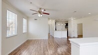 Located at 5303 S Mason Rd in Katy, TX, this two-story home offers a well-planned layout across two floors. The ground level houses an attached garage with an automatic opener, providing convenient and secure parking. The main living level features an open-concept kitchen and living room, where hardwood-style flooring flows throughout. The kitchen is equipped with stainless steel appliances, including a side-by-side refrigerator with ice and water dispenser, a dishwasher, granite countertops, rich dark cabinetry with glass-front upper doors, and a classic tile backsplash. The spacious living area is filled with natural light from multiple windows and is accented by recessed lighting and a ceiling fan. A staircase with a white balustrade adds an architectural touch to the open layout. The two bedrooms are carpeted and include ceiling fans, with one featuring an arched window for added character. The primary bedroom is generously sized and connects to a bathroom with granite countertops and dark wood cabinetry. Both closets offer shelving and hanging storage. A dedicated laundry area accommodates a full-size washer and dryer. The home's neutral color palette and consistent finishes throughout create a clean, cohesive aesthetic.