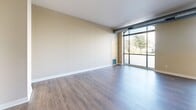 Located at 2401 Chicago Ave in Minneapolis, MN, this well-designed urban unit offers a smart, functional layout across a single floor. The open-concept kitchen and living area serves as the heart of the space, bathed in natural light streaming through a dramatic arched, floor-to-ceiling window that frames views of the surrounding neighborhood. Exposed industrial ductwork adds a loft-inspired character to the living area, complementing the warm hardwood-style flooring that runs throughout.

The kitchen is thoughtfully appointed with light maple cabinetry, dark granite countertops, stainless steel appliances including a gas range and over-the-range microwave, and a central island with pendant lighting overhead—ideal for both meal preparation and casual dining. A second kitchen and living area provides additional flexible space within the unit.

The hallway connects the living spaces to a well-organized closet with built-in shelving, offering practical storage solutions. The bathroom completes the layout, tucked efficiently within the floor plan. Neutral beige tones on the walls throughout create a clean, cohesive aesthetic that allows for versatile interior styling. The unit's compact yet open design makes excellent use of every square foot, delivering a comfortable and contemporary urban living experience.
