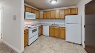 Located at 12 Heritage Ln in Leominster, Massachusetts, this single-floor unit offers a straightforward, functional layout designed for comfortable everyday living. The floor plan reveals a well-organized arrangement of interconnected spaces, with the kitchen positioned adjacent to the main living area for convenient flow.

The kitchen is equipped with warm oak-toned cabinetry providing generous upper and lower storage, complemented by white appliances including an electric range, over-the-range microwave, dishwasher, and refrigerator. Light-toned tile flooring adds a clean, practical finish to the space.

The living area is carpeted and features a coat closet near the entry door, offering immediate storage upon arrival. Baseboard heating runs along the perimeter walls throughout the unit, ensuring consistent warmth. The bedrooms are also carpeted and finished in neutral white tones, each benefiting from natural light through standard windows with outdoor views of the surrounding neighborhood. Closet space is available within the bedroom areas, including a bi-fold door closet for organized storage.

The bathroom is clean and functional, featuring a full tub and shower enclosure, toilet, and tile flooring. Throughout the unit, the consistent use of white walls, neutral carpet, and practical finishes creates a bright, understated ambiance well-suited for a variety of living arrangements.