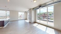 This 720-square-foot, one-bedroom, one-bathroom apartment in the Spring neighborhood of Pittsburgh, PA (15201) offers a thoughtfully designed single-floor layout with modern finishes throughout. The open-concept living and kitchen area is anchored by a large kitchen island featuring a white quartz countertop and an integrated sink, complemented by rich dark-wood cabinetry and a full suite of stainless steel appliances, including a French door refrigerator, electric range, and built-in microwave. Pendant lighting and a large floor-to-ceiling window flood the space with natural light while providing views of the surrounding neighborhood. The expansive living area showcases light hardwood-style flooring, exposed ductwork accents, and multiple oversized windows and glass doors opening to a private balcony with sweeping Pittsburgh city views. The 140-square-foot bedroom features plush carpeting, a large window with a roller shade, and balcony access, offering ample natural light. Built-in shelving provides convenient storage. The full bathroom is finished with tile flooring, a dark-wood vanity with quartz countertop, a large mirror, and a full soaking tub and shower combination.