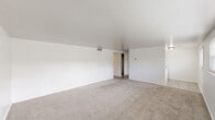 Located at 549 5th St SE in Barberton, Ohio, this single-floor, one-bedroom, one-bathroom unit offers a well-organized layout that makes efficient use of its space. The living room is generously sized, featuring light gray carpeting, white walls with a subtle block texture, and a window with blinds that allows natural light to filter in and offers a view of the surrounding greenery outside.

The combined kitchen and dining area is finished with light wood-style vinyl flooring and includes white cabinetry, granite-style countertops, a gas range, and a single-basin sink — providing a functional cooking space. The open wall-block accent adds a clean, utilitarian character to the area.

The bedroom is carpeted and bright, with smooth white walls and a built-in closet with louvered doors, along with an additional closet for ample storage. High ceilings in the bedroom area contribute to an open, airy feel.

The bathroom is clean and well-lit, featuring a window with blinds for natural light, a vanity with a white basin, a toilet, and a bathtub/shower combination with tiled surround. Wood-style flooring ties the space together.

Additional practical spaces include a dedicated laundry area, a utility room, and a hallway connecting the rooms. Throughout, the neutral white palette and light flooring create a bright, cohesive atmosphere.