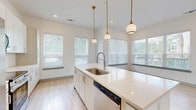 This well-appointed 3-bedroom, 2-bathroom single-story home offers a clean, modern aesthetic throughout its thoughtfully designed layout. The open-concept kitchen serves as the heart of the home, featuring white cabinetry, a herringbone tile backsplash, stainless steel appliances, and a large center island with quartz countertops and an undermount sink. Elegant gold pendant lights hang above the island, complementing the warm light wood flooring that extends through the main living areas. Expansive windows flood the kitchen and living spaces with natural light and offer views of surrounding greenery.

Each of the three bedrooms is carpeted for comfort and includes generous windows that invite natural light. The spacious primary bedroom benefits from its own dedicated closet, while two additional closets serve the remaining bedrooms. All three closets feature built-in wire shelving for practical storage.

The two bathrooms are finished with light wood-look flooring, light wood vanity cabinetry, and quartz countertops. One bathroom includes a glass-enclosed walk-in shower with herringbone tile, while the second features a shower-tub combination with matching tile. Crisp white walls and chrome fixtures complete the clean, contemporary look throughout the entire home.