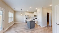 Located at 4040 Candleberry Gdn in North Augusta, SC, this two-story home offers a clean, contemporary design throughout both levels. The main floor features a well-appointed kitchen as its centerpiece, showcasing crisp white shaker-style cabinetry, a subway tile backsplash, light wood-look flooring, and a contrasting gray center island with a white quartz countertop and single-basin sink. Stainless steel appliances, including a French door refrigerator, electric range, microwave, and dishwasher, complete the kitchen. A geometric pendant chandelier adds an elegant touch above the island. A half bathroom on the main level provides added convenience, while the attached garage offers generous storage and parking space, equipped with an automatic opener and electrical panel access. The staircase, brightened by a window that draws in natural light, leads to the upper floor, where carpeted bedrooms are fitted with ceiling fans. A full bathroom upstairs includes a tub-shower combo and wood-look flooring. Neutral tones, recessed lighting, and white trim carry throughout the home, creating a cohesive and inviting atmosphere. The backyard, visible from the 3D overview, is enclosed by a fence and features a grassy lawn.
