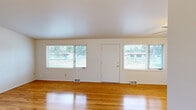 Located at 6705 S Fanazick Pl in Spokane, WA, this single-story, 3-bedroom home offers a well-organized layout with a clean, functional design throughout. The bright and open living area is defined by vaulted ceilings and gleaming hardwood floors that extend through the main living spaces. Large windows along the front of the home invite abundant natural light and provide views of the surrounding neighborhood greenery, enhancing the airy feel of the interior. The primary bedroom is generously sized, featuring hardwood flooring, a wall sconce light fixture, and its own closet. The additional bedrooms are similarly appointed with hardwood floors and closet storage. A dedicated laundry room is outfitted with cabinetry and includes space for a full-size washer and dryer, with tile flooring for easy maintenance. The kitchen connects conveniently to the laundry and living areas. Two hallways provide smooth circulation throughout the home, and two closets offer additional storage. The attached garage spans two bays with a concrete floor and exposed stud walls, providing ample room for vehicles and extra storage. The home's neutral palette and consistent hardwood flooring create a cohesive and move-in ready environment.