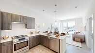 This thoughtfully designed single-floor residence offers a seamless blend of modern aesthetics and functional living. The open-concept layout connects the kitchen and living area, creating a bright, airy atmosphere enhanced by generous natural light streaming through expansive floor-to-ceiling windows.

The kitchen is outfitted with sleek dark wood cabinetry, white quartz countertops, and premium stainless steel Bosch appliances, including a gas range, French door refrigerator, and dishwasher. Pendant lighting above the peninsula adds a refined touch, while light wood-style flooring grounds the space with warmth.

The living area is a highlight of the residence, featuring large corner windows that frame breathtaking panoramic views of the waterfront, beach, and surrounding cityscape — a striking backdrop that floods the room with natural light throughout the day.

The bedroom is a serene retreat, carpeted for comfort and fitted with a sizable window offering sweeping city views. The bathroom is elegantly finished with full marble-style porcelain tile on both the floors and walls, a glass-enclosed walk-in shower, and a modern vanity, creating a spa-like atmosphere.

Throughout, the residence maintains a clean, neutral palette with contemporary finishes, delivering a polished and inviting living environment.