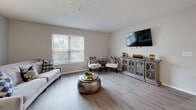 This well-appointed 2-bedroom, 2-bathroom residence in Columbus, Ohio offers a thoughtfully designed single-floor layout that maximizes functionality and comfort. The open-concept living and dining area is anchored by light wood-style flooring, neutral toned walls, and a decorative textured ceiling, creating a bright and welcoming atmosphere. Large windows throughout allow ample natural light to fill the space. The kitchen is efficiently laid out with white cabinetry, dark countertops, stainless steel appliances including a refrigerator, range, and built-in microwave, all flowing seamlessly into the dining and living areas. The living room offers generous space for relaxation and entertaining, complemented by a wall-mounted TV setup and access to natural light. Both bedrooms feature plush carpeting, closet storage, and windows overlooking the outdoors, with the primary bedroom offering a notably spacious feel. The two bathrooms are finished with white vanities, dark countertops, and light flooring. Additional conveniences include a dedicated laundry room, utility room, hallway, and four closets throughout. This residence provides a practical and comfortable living environment in a well-structured layout.