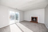 This single-floor residence offers a well-organized layout that balances comfort and functionality throughout. The living room serves as the heart of the home, anchored by a classic brick fireplace with a white painted mantle and raised brick hearth, providing a warm focal point for the space. Plush carpeting, neutral gray walls, and a textured ceiling complement the room's inviting atmosphere. Large sliding glass doors flood the living area with natural light and open directly onto a wood-deck balcony, offering pleasant outdoor views.

The kitchen is thoughtfully updated, featuring rich dark cabinetry, granite-look countertops, a crisp white subway tile backsplash, wood-look luxury vinyl plank flooring, and a full suite of black appliances including a refrigerator, range, and built-in microwave. A window above the sink adds additional natural light to the space.

The bedrooms are carpeted and finished with neutral tones, each equipped with windows that bring in ample daylight. One bedroom benefits from a spacious walk-in closet outfitted with dual hanging rods and shelving on three walls, offering generous storage capacity.

The bathroom includes a dark vanity with granite-look countertops, a tub-shower combination, and wood-look tile flooring. A dedicated laundry room with hardwood-style flooring provides washer and dryer hookups, adding everyday convenience to this well-appointed home.