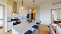 Located at 110 N First St in Minneapolis's dynamic North Loop neighborhood, this contemporary residence offers a thoughtfully designed single-floor layout with an open-concept living area, two bedrooms, and two bathrooms. The living and dining space is bathed in natural light through expansive floor-to-ceiling windows that frame sweeping city and treetop views. Exposed industrial ductwork runs along the ceiling, adding an urban loft character that complements the light hardwood flooring throughout. A ceiling fan and track lighting provide functional illumination, while globe pendant lights above the kitchen island serve as a stylish focal point. The kitchen is well-appointed with white shaker cabinetry, a classic subway tile backsplash, stainless steel appliances including a gas range and built-in dishwasher, and a spacious waterfall-edge island with bar seating. Both bedrooms are bright and serene, each benefiting from large windows with urban outlooks and light wood flooring. The primary bathroom features an extended vanity with generous cabinet storage and a large mirror, finished with neutral tile flooring. The second bathroom offers a clean, functional design with a shower-tub combination. This residence seamlessly blends industrial-modern aesthetics with comfortable, contemporary living in the heart of Minneapolis.
