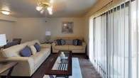 This single-floor residence offers a comfortable and practical layout designed for everyday living. The living room serves as the central gathering space, featuring plush wall-to-wall carpeting, a ceiling fan with light fixture, and a large sliding glass door fitted with vertical blinds that fills the room with natural light. The open feel of the living area is complemented by a textured ceiling and ample room for seating arrangements.

The kitchen is efficiently designed with wood-toned cabinetry, dark granite-style countertops, wood-look vinyl flooring, a white electric range, and a full-size black refrigerator — providing all the essentials in a compact, functional space.

Both bedrooms are carpeted and include ceiling fan light fixtures and windows that allow in natural light. Each room offers adequate space for a full-sized bed and additional furniture, with closet access nearby.

The two bathrooms are well-appointed, each featuring wood-look vinyl flooring, warm wood vanity cabinetry with dark countertops, and a shower/tub combination. The vanity areas include mirrored storage and overhead lighting, creating a clean and functional environment.

Overall, this residence presents a cohesive, practical layout with consistent finishes throughout, making it a comfortable and move-in ready space.