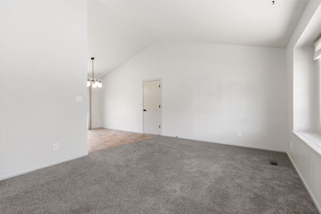 Vaulted living room. Door to attached 2-car garage. - 1956 Promenade Way
