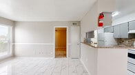 Located at 8600 S Course Dr in Houston, TX, this single-floor home offers two bedrooms and two bathrooms within a well-organized layout. The living and dining areas are finished with large-format marble-look porcelain tile flooring that lends a clean, bright aesthetic throughout the common spaces. A chair-rail detail along the walls adds a classic architectural touch.

The kitchen features a pass-through granite countertop breakfast bar, gray cabinetry with mosaic tile backsplash, a white range, and a stainless steel refrigerator. It opens seamlessly to the dining area, which is lit by a pendant light and benefits from natural light through a window with blinds.

Both bedrooms are carpeted for comfort and feature neutral gray walls, ceiling fans, and windows that allow natural light in. The primary bedroom is a generous size and includes a dedicated walk-in closet outfitted with built-in wire shelving and basket storage for organized living.

The bathrooms are finished with marble-look tile flooring, granite-topped vanities, and a tiled tub-shower combination. The overall ambiance of the home is light, neutral, and move-in ready, with consistent finishes that create a cohesive and functional living environment throughout.