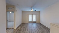 This single-floor residence offers a well-designed open-concept layout that seamlessly connects the living, dining, and kitchen areas. The main living space features wood-look plank flooring, neutral-toned walls, and a ceiling fan, with natural light streaming through French doors that open to the outdoors. A half-wall partition defines the transition between the living area and the kitchen zone, maintaining an airy, connected feel throughout.

The kitchen is a standout feature, equipped with white shaker-style cabinetry, granite countertops, a subway tile backsplash, and a full suite of stainless steel appliances including a refrigerator, range, microwave, and dishwasher. A peninsula with an undermount sink and pendant lighting above adds both functionality and visual appeal.

The bedrooms are carpeted for comfort and include ceiling fans and multiple windows that invite natural light. One bedroom features two separate doors, suggesting access to a closet and an adjoining space. The bathroom is finished with granite countertops on white cabinetry, a large framed mirror, and a tub-shower combination with decorative tile surround and wood-look tile flooring, completing the cohesive, modern aesthetic found throughout the space.